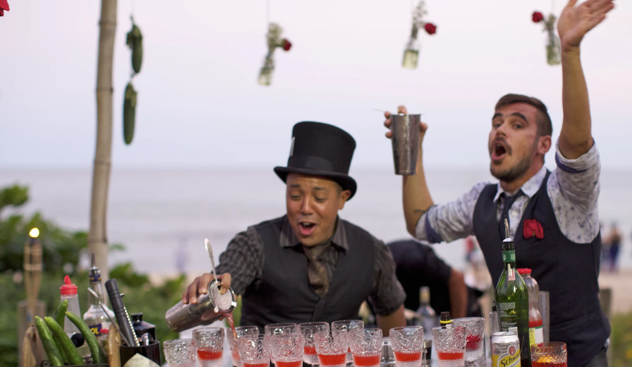 Dois bartenders com cartolas durante uma dinâmica de preparo de coquetéis.