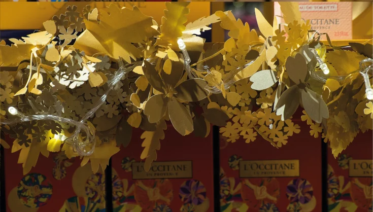 Detalhe de folhagens e ornamentos dourados na ambientação de Natal da L’Occitane.